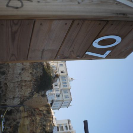 Foto de uma estrutura de madeira a esquerda com o número 07 colado. Ao fundo um casarão em cima de uma rochedo.